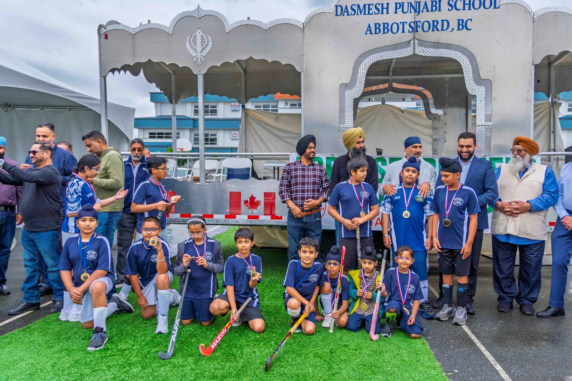 Young AFHC players wearing their medals alongside coaches and club supporters at Dasmesh Punjabi School in Abbotsford