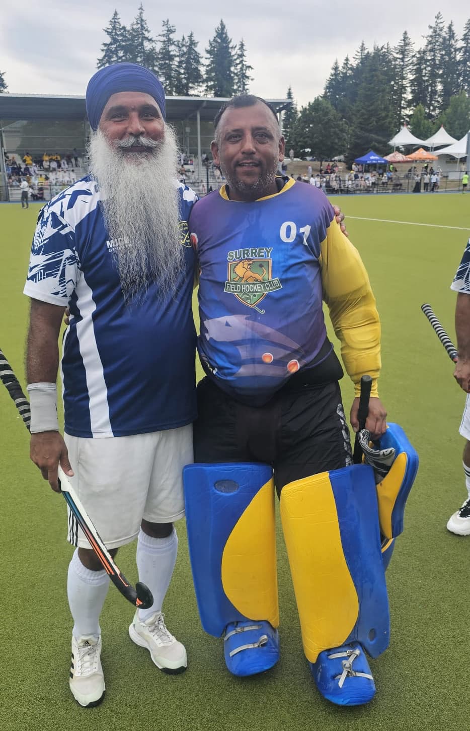The goalkeeper in full kit, blue and yellow leg guards and kickers, standing arm in arm with a teammate on the pitch after the final