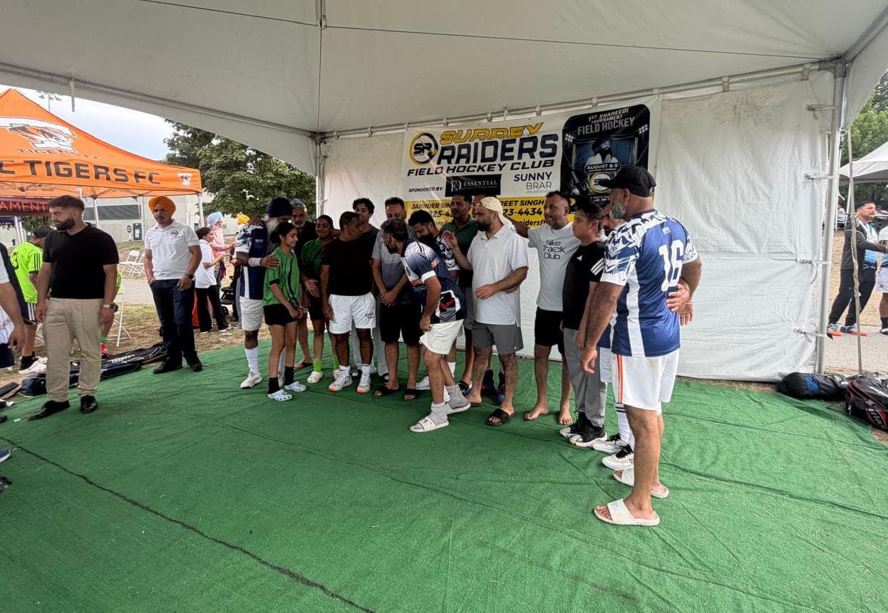 Players and supporters lined up under the tournament tent for the trophy presentation, the Surrey Raiders banner behind them