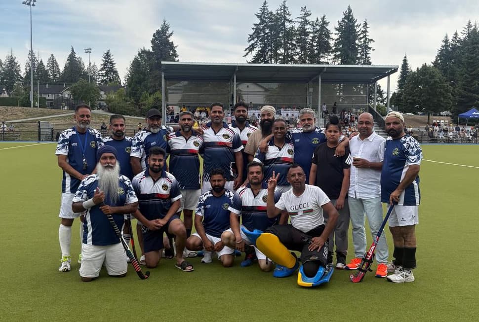 The Abbotsford Field Hockey Club squad posed together on the turf after the final, goalkeeper pads laid out in front and the covered stand behind them